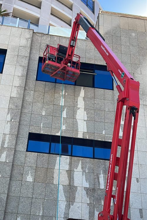Limpieza de fachada en altura en Castellón con plataforma elevadora y cristales exteriores de edificio.