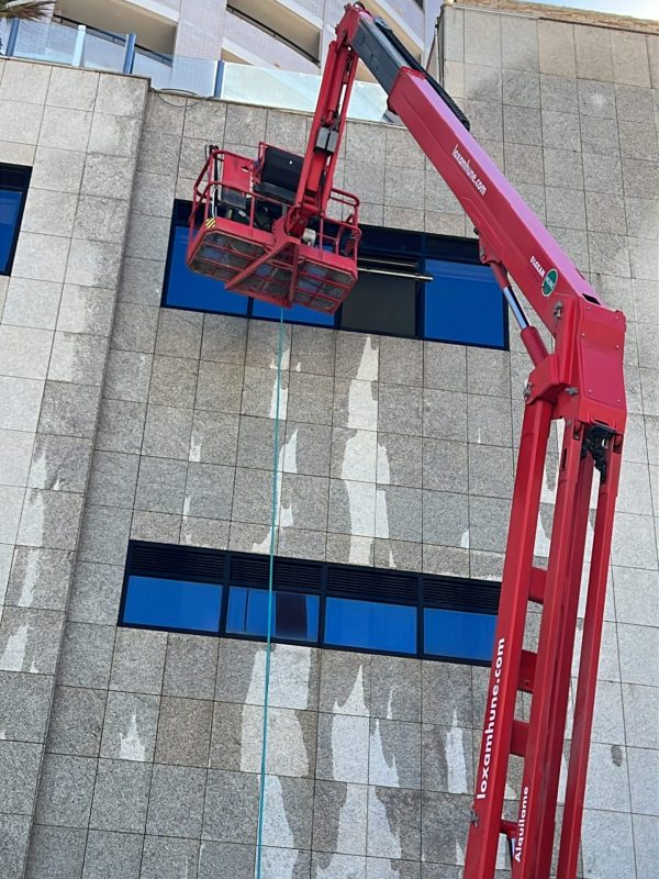 Limpieza de fachada en altura en Castellón con plataforma elevadora y cristales exteriores de edificio.
