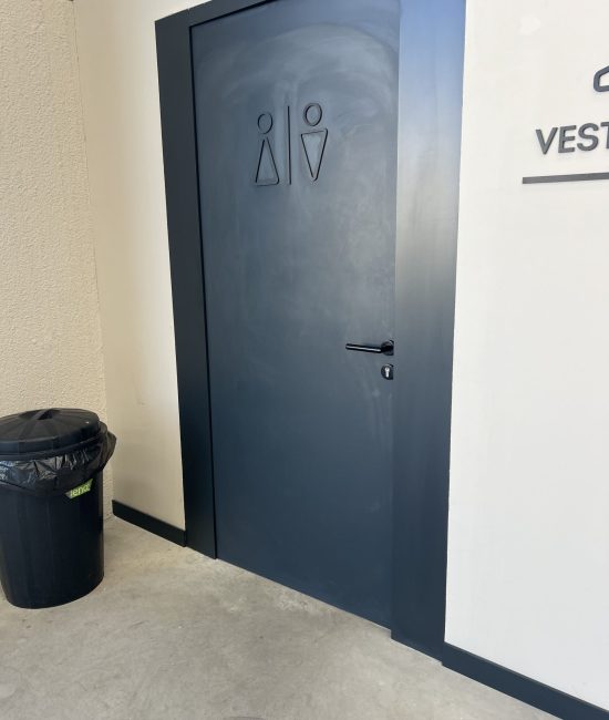 Limpieza de aseos y vestuarios en Castellón con puerta señalizada, suelo limpio y zona de paso cuidada.
