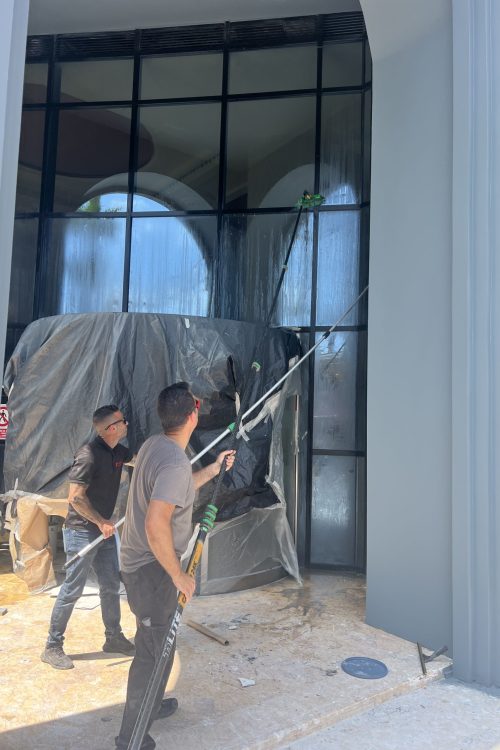 Limpieza de cristales en Castellón con trabajadores usando pértigas profesionales en edificio comercial durante servicio de mantenimiento.